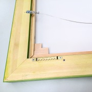Rückseite eines Schattenfugenrahmens mit eingebautem Leinwandbild. Zackenaufhänger und Drahtaufhängung sichtbar. Keile für Keilrahmenspannung ebenfalls sichtbar.